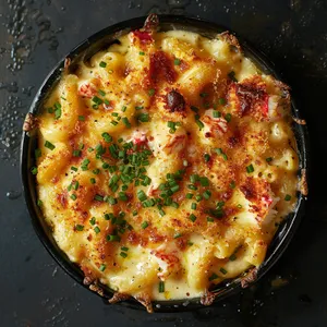 From above, you see a golden-brown, bubbly surface, with specks of green from the snipped chives. The crust cradles sumptuous, creamy pasta dotted with chunks of pinkish-white lobster meat. A drizzle of truffle oil gives it an inviting and gourmet glossy finish.
