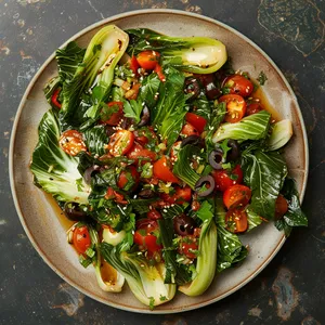 A dazzling plate, featuring a heap of glossy green baby bok choy leaves stir-fried to tender-crisp. Its charm is intensified with the ruby red of a fresh Mediterranean salsa, comprising chopped tomatoes, kalamata olives, and fresh parsley. A sprinkle of toasted sesame seeds tops the dish for a pleasing crunch and deep, nutty aroma.