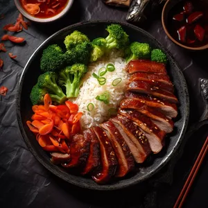 Sliced pork shoulder with a bright red glaze served with steamed white rice and stir-fried vegetables on a rectangular plate.
