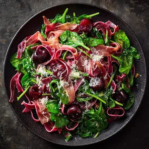 Glistening red and deep purple cherries artfully scattered atop a bed of vibrant, fresh green spinach fettuccine, interspersed with bits of dusky pink prosciutto and flecks of white parmesan.