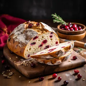 A hearty, rustic loaf with a crispy, golden brown crust. The interior reveals a canvas of warm ivory sourdough studded with cranberries, their color a vibrant contrast. Scattered walnut pieces add a rich earthiness. The bread is sliced thickly, revealing the fluffy yet structured inner crumb.