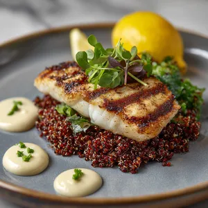 Flickers of grill marks on white sea bass gently resting on a bed of ruby red quinoa, speckled with bits of green herbs. Plated beautifully with a radiant orb of lemon to its side, dollops of off-white aioli adding contrast while a sprinkle of finely chopped greens brings a 'pop' of color.