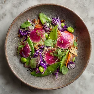 A riot of colors on a plate, the translucent pink clams are nestled cozily amongst crunchy green snow peas, and vibrant purple cabbage. Radish roses and edamame pods are strewn about. White sesame seeds generously sprinkled all over give an appealing contrast, while coriander leaves add a fresh green touch. A mixed grain sesame cracker serves as a photogenic side.