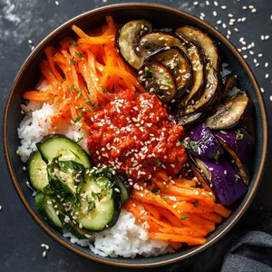 A stylish bowl brimming with a kaleidoscope of colors from roasted winter vegetables. Deep purple roasted eggplant and bright orange carrots converge with green zucchini and white mushrooms, all nestled atop a bed of fluffy white rice. Bright red, spicy miso paste adorns the top, garnished with black and white sesame seeds.