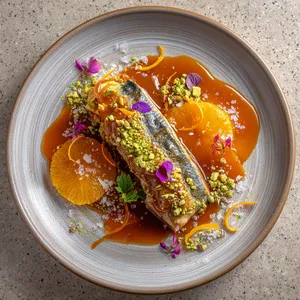 From above, your eyes will be greeted with a beautiful platter featuring a stunningly seared mackerel with a glossy orange-date caramel glaze. Accents of crushed pistachios add a delightful crunch and vivid pop of green amid the bold colors of the fish and caramel. Ribbons of lemon zest and a sprinkle of sea salt crystals seal the deal on this Instagram-worthy masterpiece.