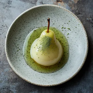 A translucent, amber-hued pear sitting on a pool of light-green matcha-infused syrup, glistening under the drizzle of golden honey. Topped off with a light dusting of Matcha powder, creating an intriguing contrast between the Matcha's vivacious green and the pear's gentle glow.