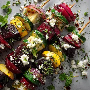 A vibrant kaleidoscope of fire-kissed beets, zucchini, and onion pieces, alternated on skewers and drizzled with creamy white feta. A sprinkle of finely chopped parsley and mint brings a pop of green and smells divine.