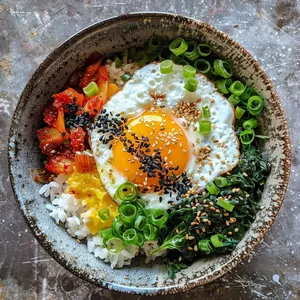 A picturesque array of vibrant veggies and glistening nettles atop steamy, white rice in a deep, stoneware bowl. A sunny-side-up egg, with its gleaming, golden yolk, sits at the center while gochujang spice mix gives the dish a fiery red border. Garnished with black sesame seeds and green onion slices sprinkled on top for a photogenic finish.