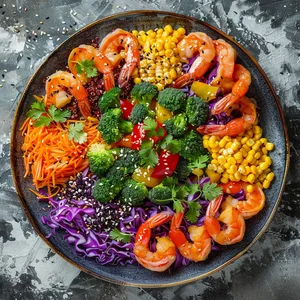 A mandala-like plate centered on a mound of tricolor quinoa, scattered with vegetables like a painter's palette: red bell pepper, yellow corn, green broccoli, and purple cabbage. Orange-glazed shrimp arranged around it. Topped with black sesame and bright sprigs of fresh cilantro give it a final touch of contrast.