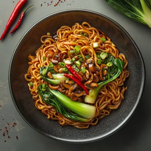 From above, it's a splendid tableau of long golden noodles strewn with glossy shiitake slices and vibrant green Bok Choy leaves. The garnish of bright red chillie and spring onion rings brings festive pops of color for an arresting visual.