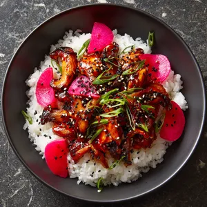 A strikingly colorful dish, between the glistening caramelized oyster mushrooms painted with shiny red-spicy gochujang glaze and the vibrant pink pickled radishes scattered around. It's all served on a warm bed of white jasmine rice draped with sprinkles of black and white sesame seeds and vibrant green scallion slits.